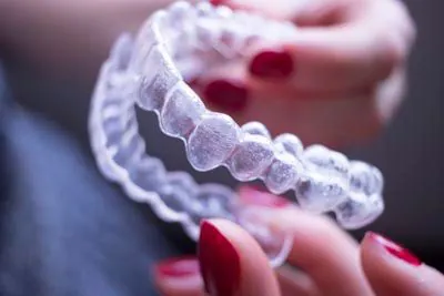 Hands holding a clear Invisalign aligner